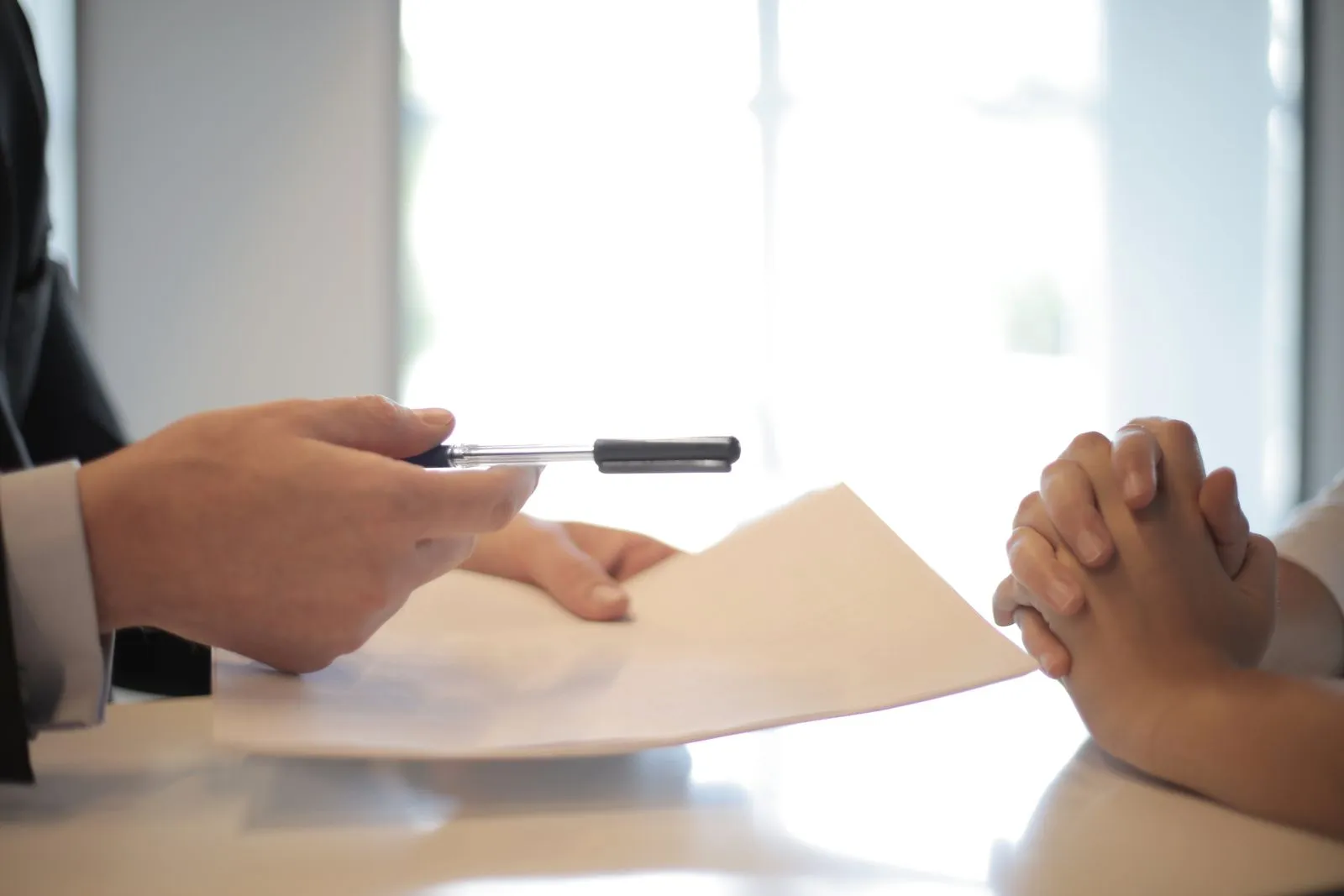An adviser passing a document across an office table during a meeting